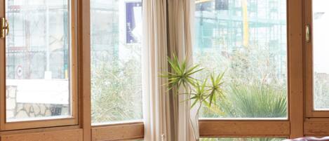 Una habitación con ventanas amplias, sillones de cuero, una pequeña mesa y una planta en maceta.