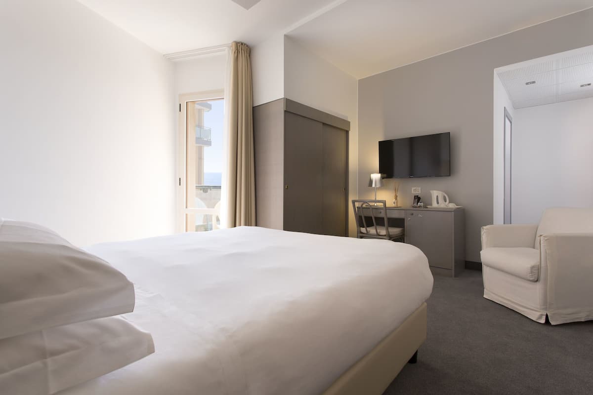 Een hotelkamer met een groot bed, een bureau met stoel, een televisie en een bank.