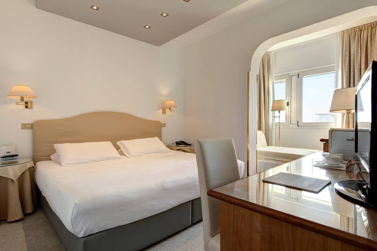 Een hotelkamer met een bed, nachtkastjes, een bureau en een televisie.