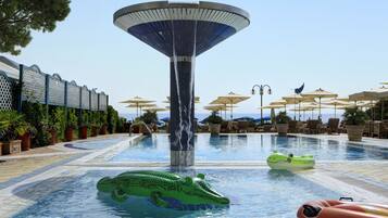Una piscina al aire libre, sombrillas, sillones reclinables de piscina