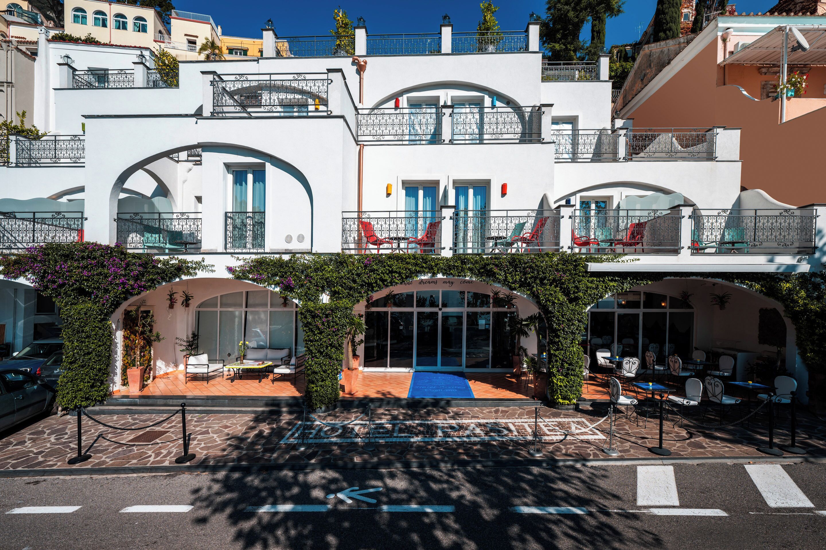 A hotel with a covered outdoor seating area, a blue carpet, and a sign that reads 'dreams may come.'