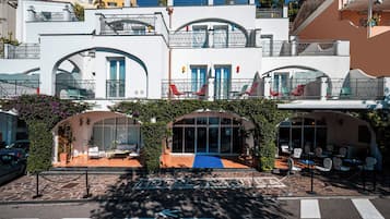 A hotel with a covered outdoor seating area, a blue carpet, and a sign that reads 'dreams may come.'