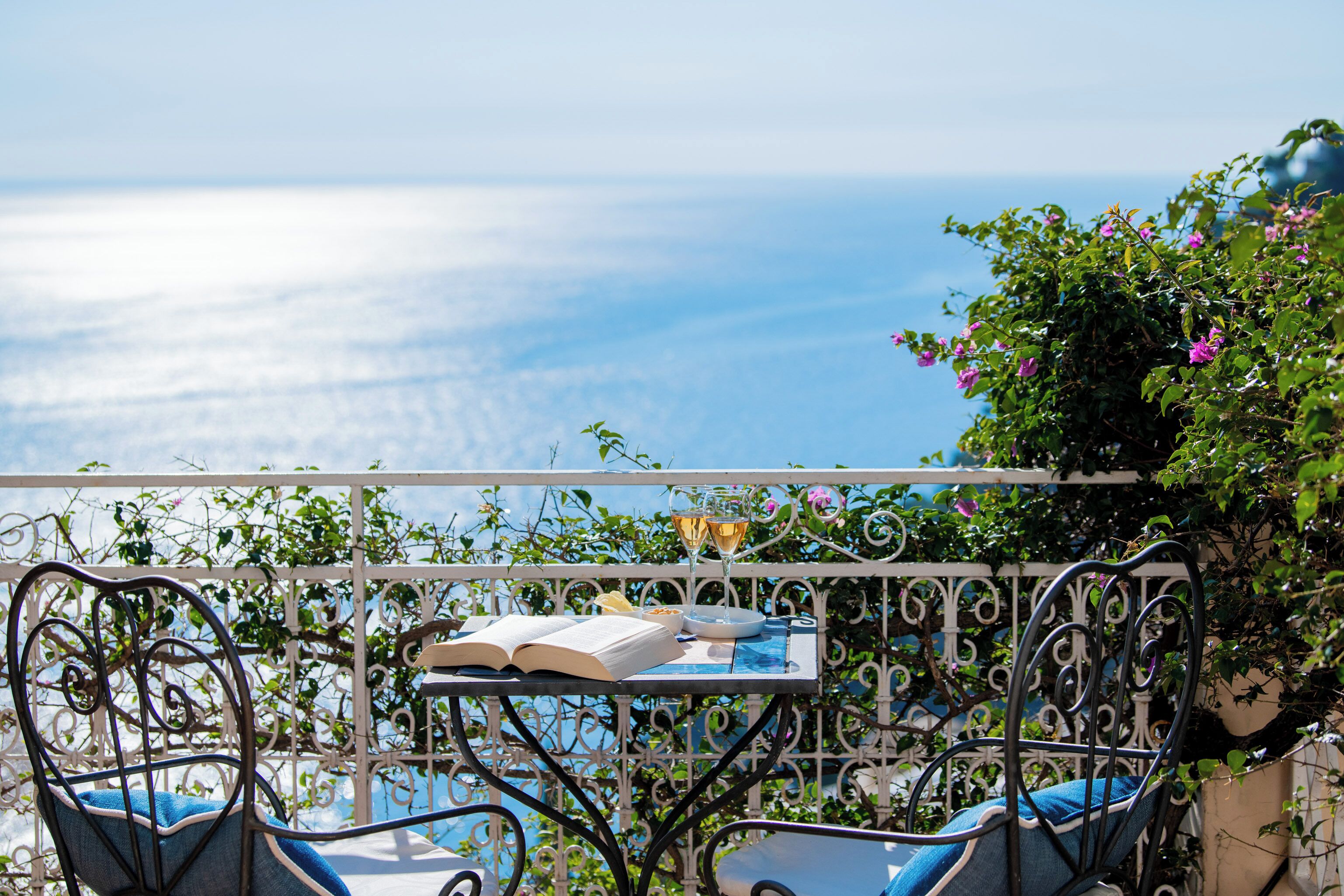 A balcony with a table, chairs, and a book.