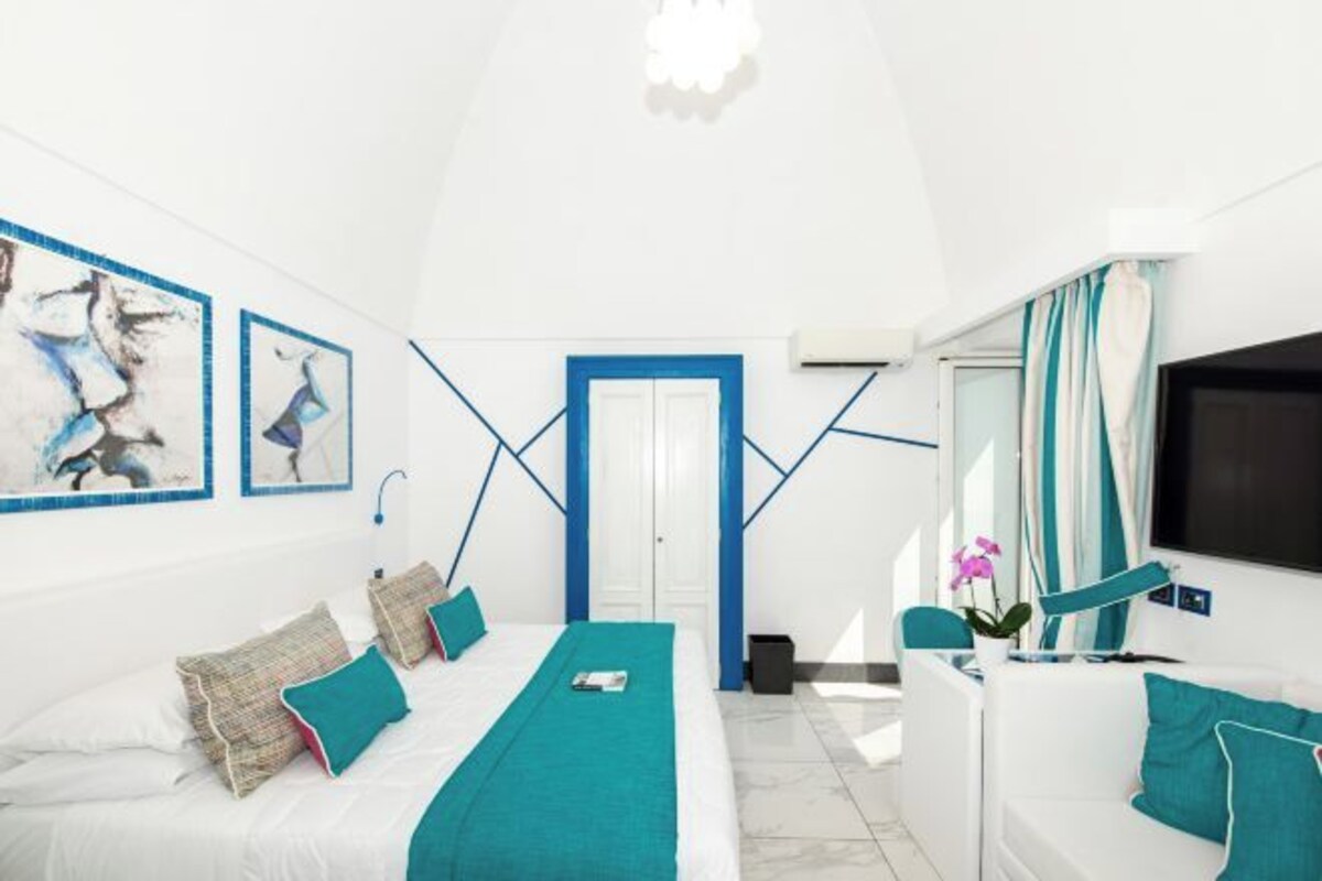 Una habitación de hotel moderna con cama, sofá, televisor y obras de arte en las paredes.