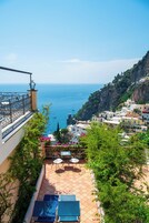 Una terraza con vistas al mar, un balcón con barandilla y suelo de baldosas.