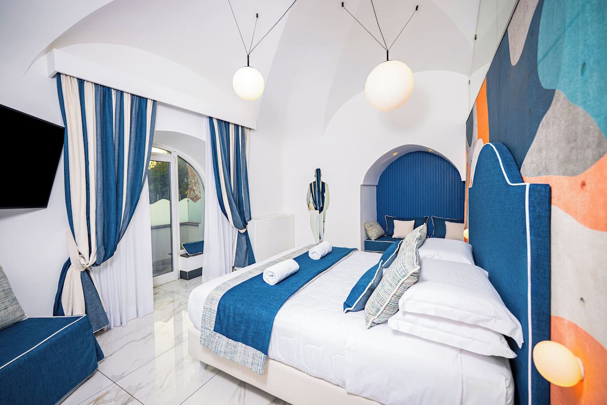 A modern bedroom with a bed, curtains, a TV, and a vase.