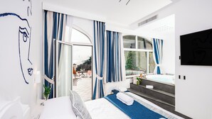 Habitación de hotel moderna con una cama grande, vistas al exterior, una zona de estar con una mesa y sillas, y un jacuzzi.