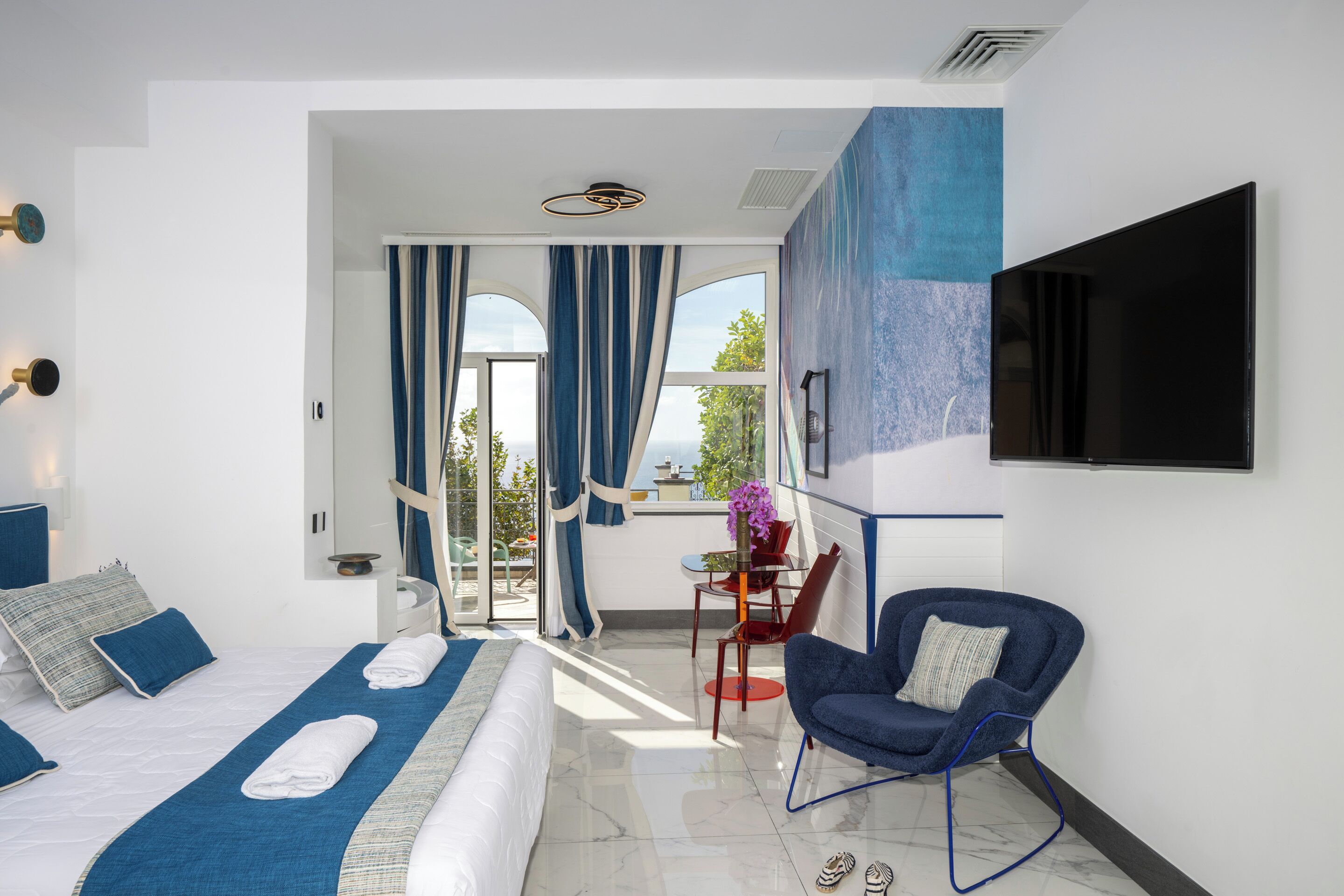 Une chambre d’hôtel moderne équipée d’un lit, d’une télévision, d’une chaise et offrant une vue sur l’extérieur.