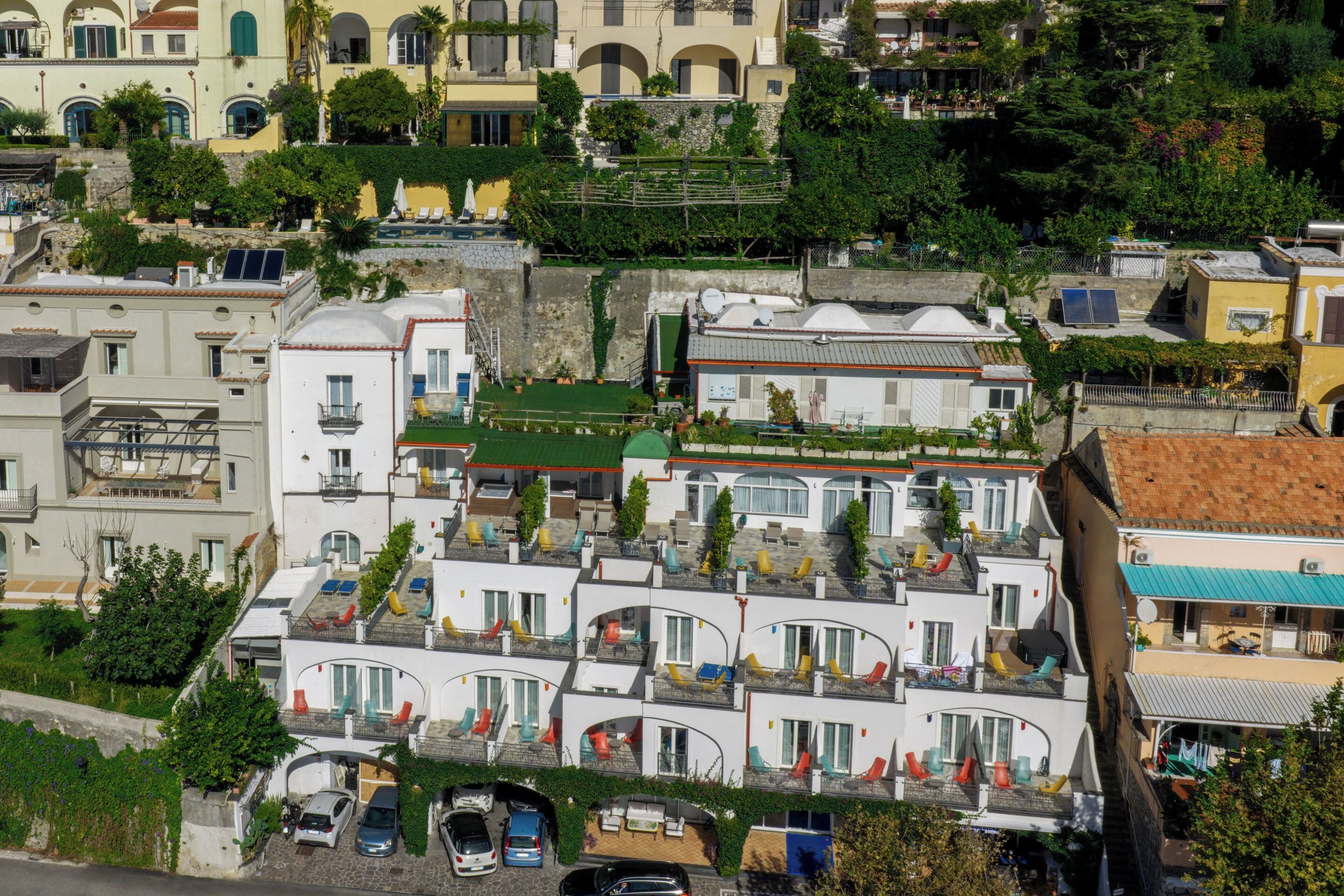 Un edificio a più piani con balconi, una terrazza sul tetto e un’area di parcheggio.