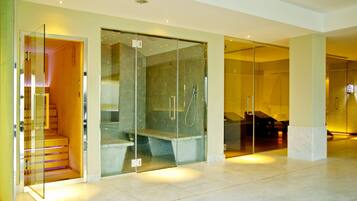 A modern hotel lobby with a glass-enclosed shower area, marble flooring, and a wooden staircase.