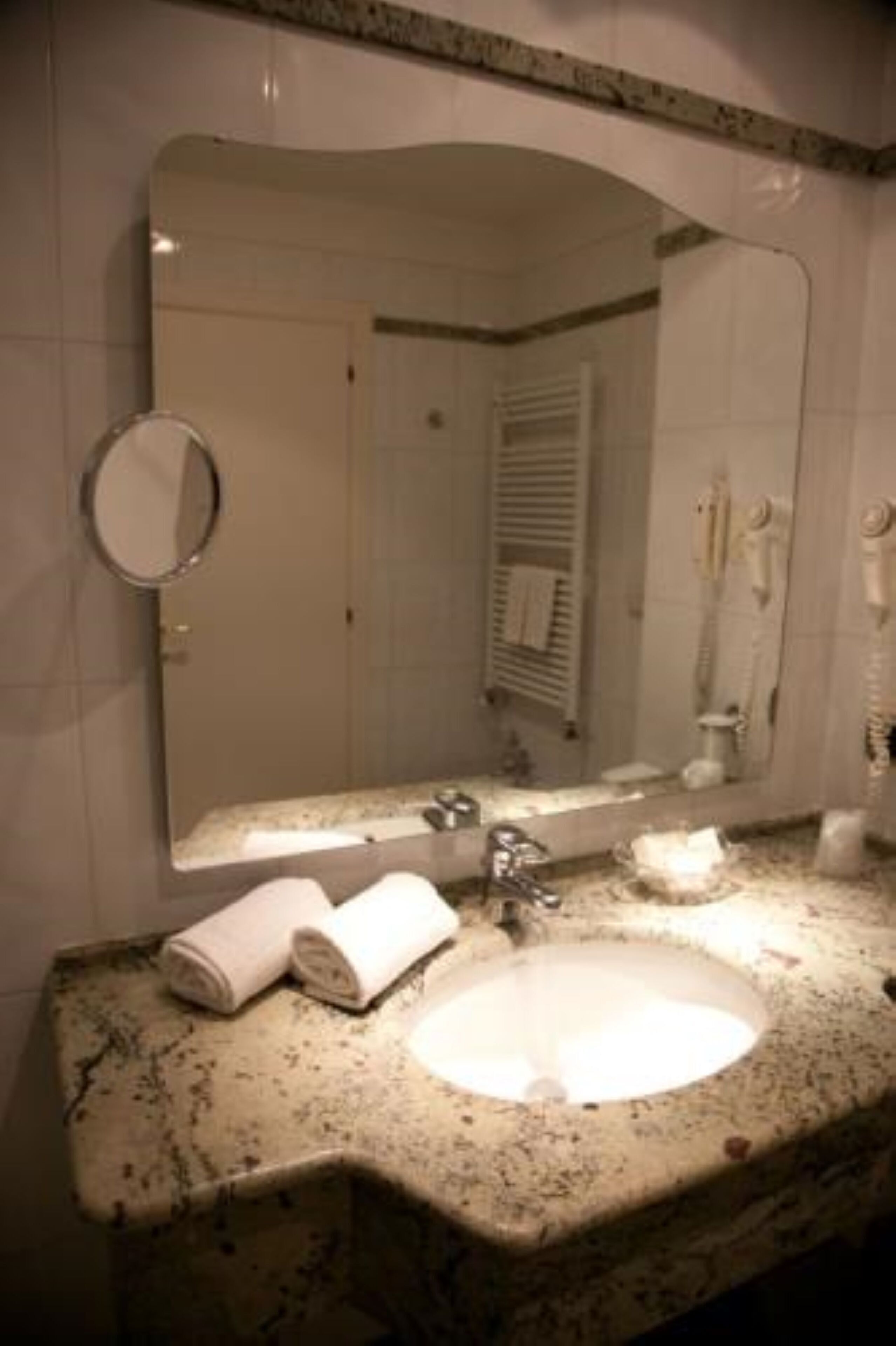 Ein Badezimmer mit Granitplatte, Waschbecken, Spiegel und Handtuchhalter.