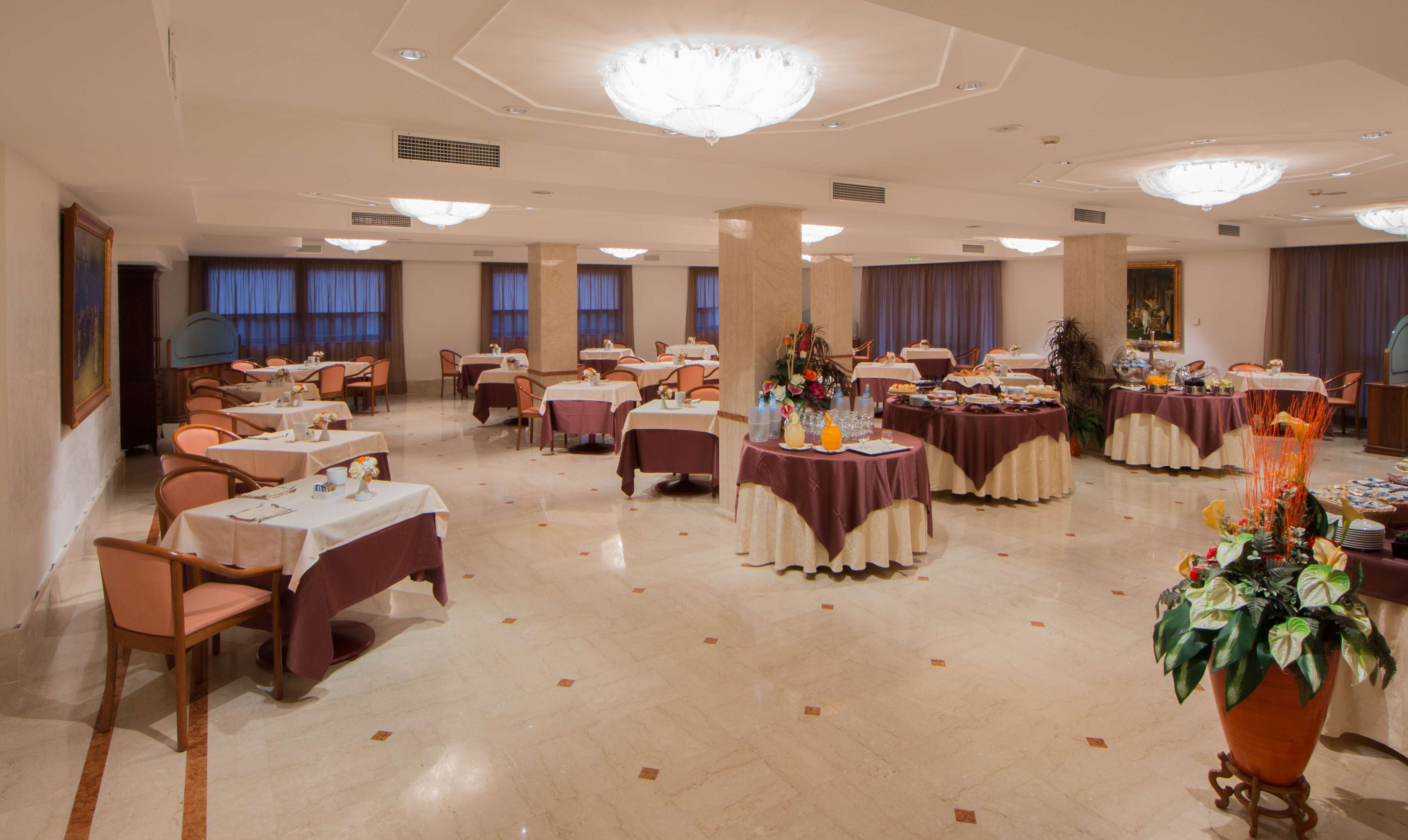 Ein Festsaal mit runden Tischen, Stühlen und einem großen Blumenarrangement.