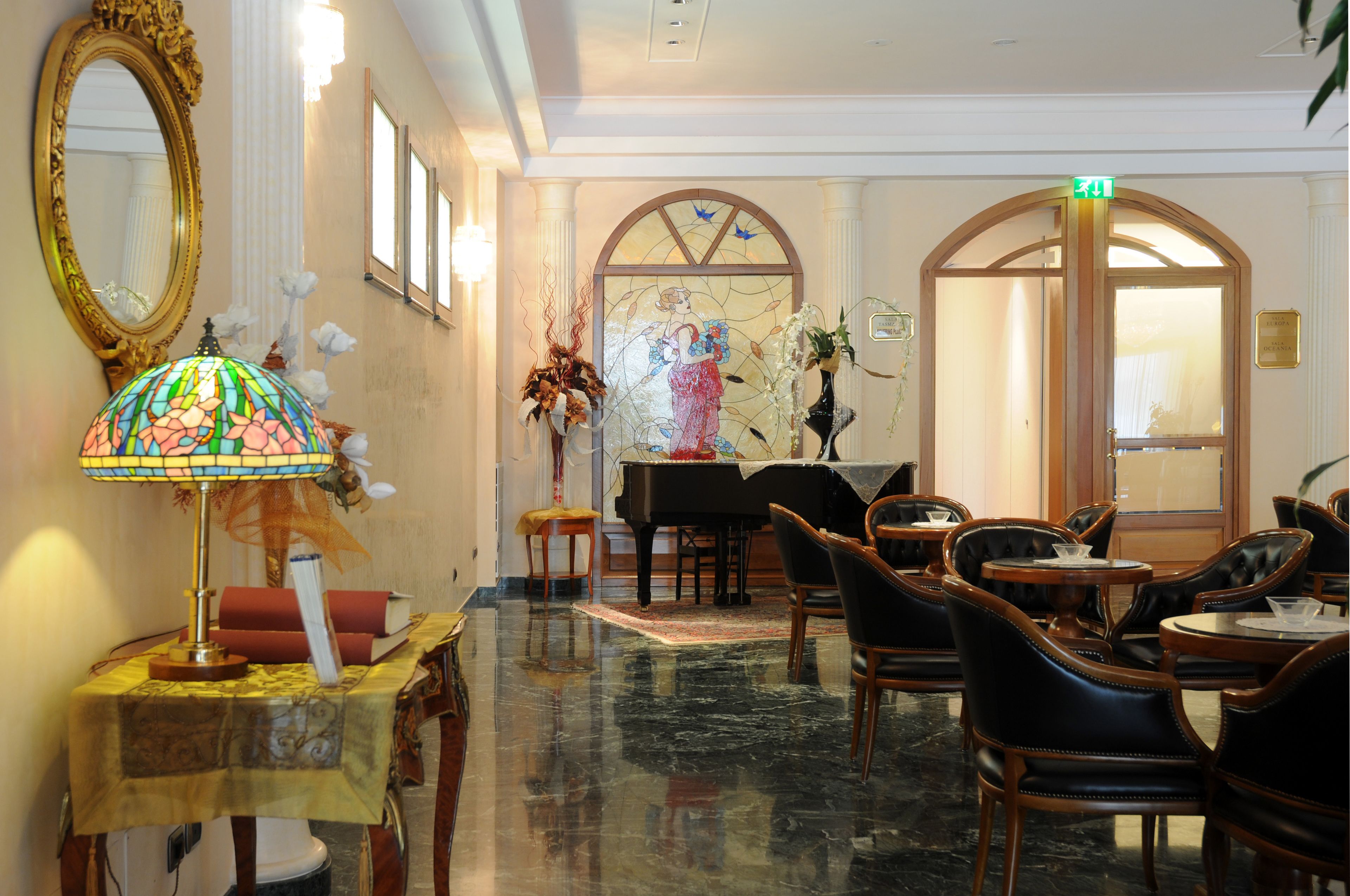 Eine Lobby mit Klavier, Sitzgelegenheiten und einem großen Spiegel.