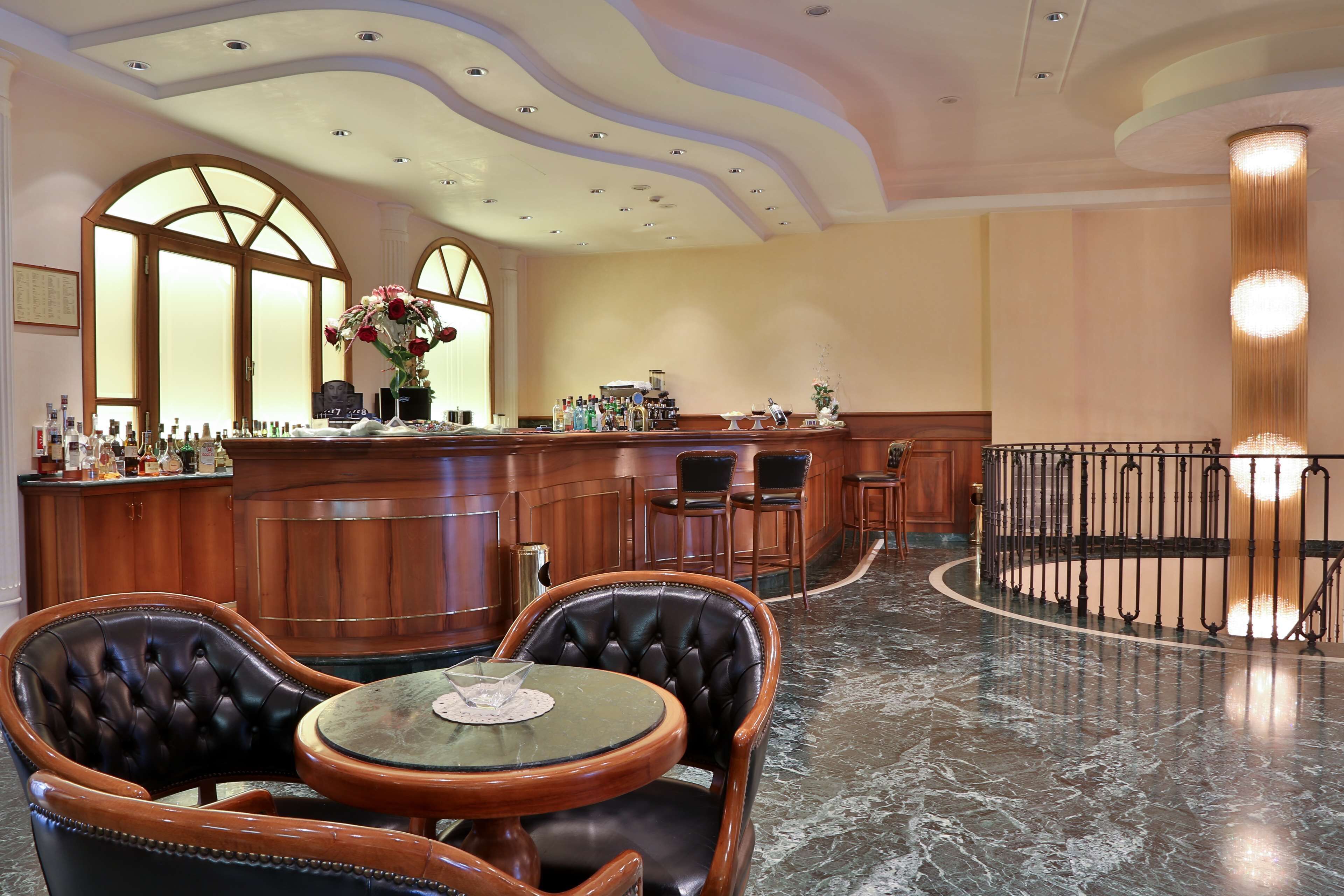 Zona de bar con sillones de cuero, piso de mármol y barra con distintos tipos de botellas.