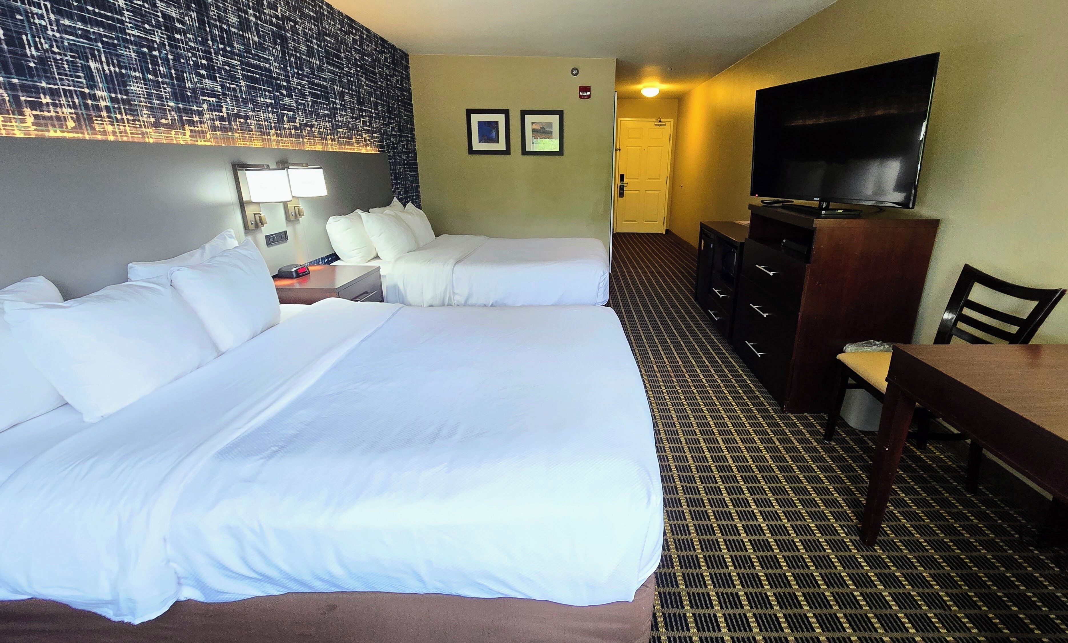 Habitación de hotel con dos camas, televisión, escritorio y cómoda.