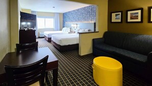 A hotel room with a bed, a sofa, a dining table with chairs, a TV, and a yellow ottoman. - Comfort Inn Fort Collins North (Fort Collins)