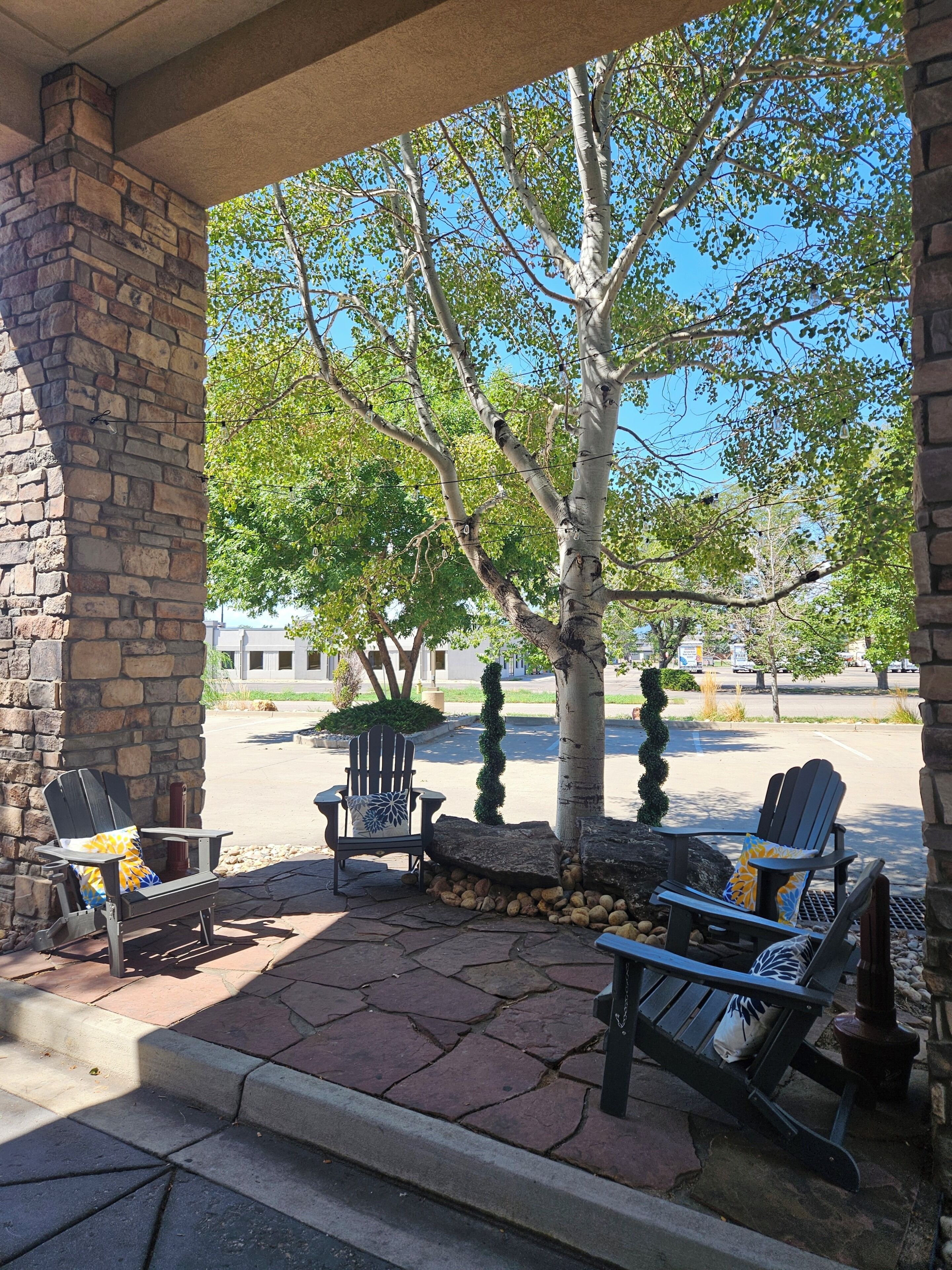 A covered outdoor seating area with Adirondack chairs and a stone wall.