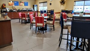 A spacious dining area with multiple tables and chairs, a coffee station, and a view of the outside through large windows. - Comfort Inn Fort Collins North (Fort Collins)