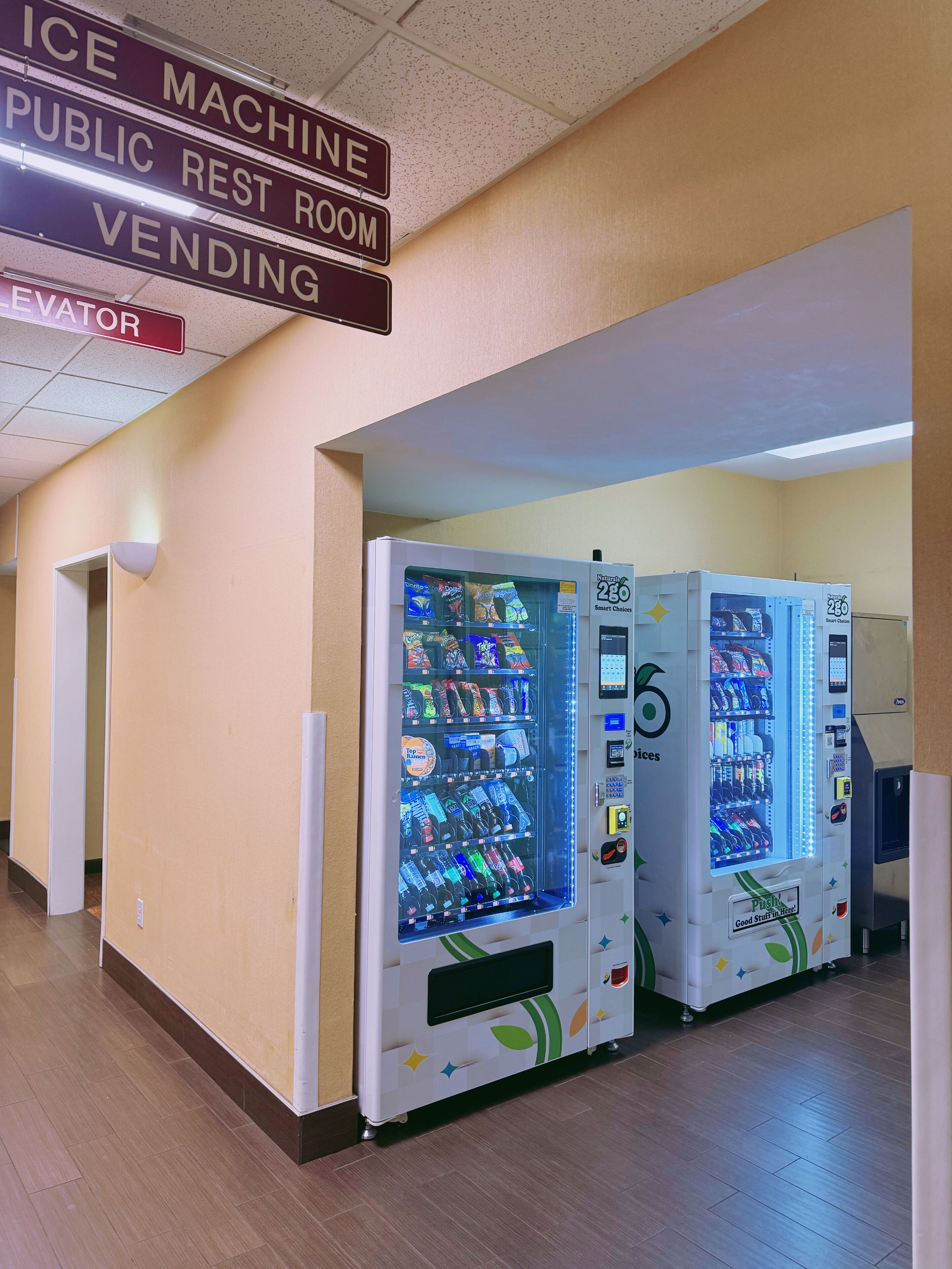 A hallway with vending machines and a sign indicating an ice machine, public rest room, and vending area.