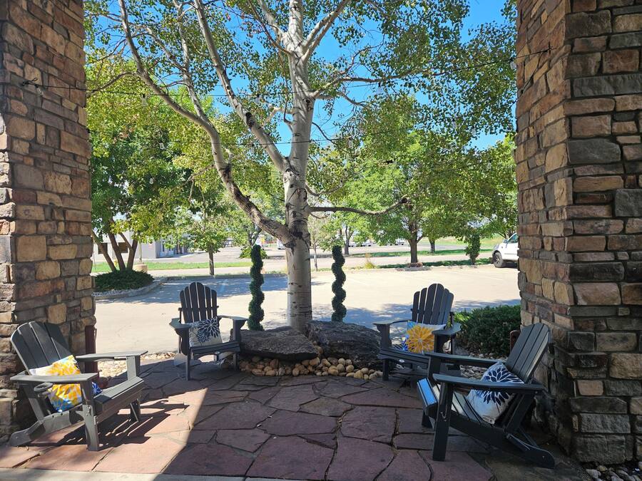 A covered patio area with Adirondack chairs and a stone floor.