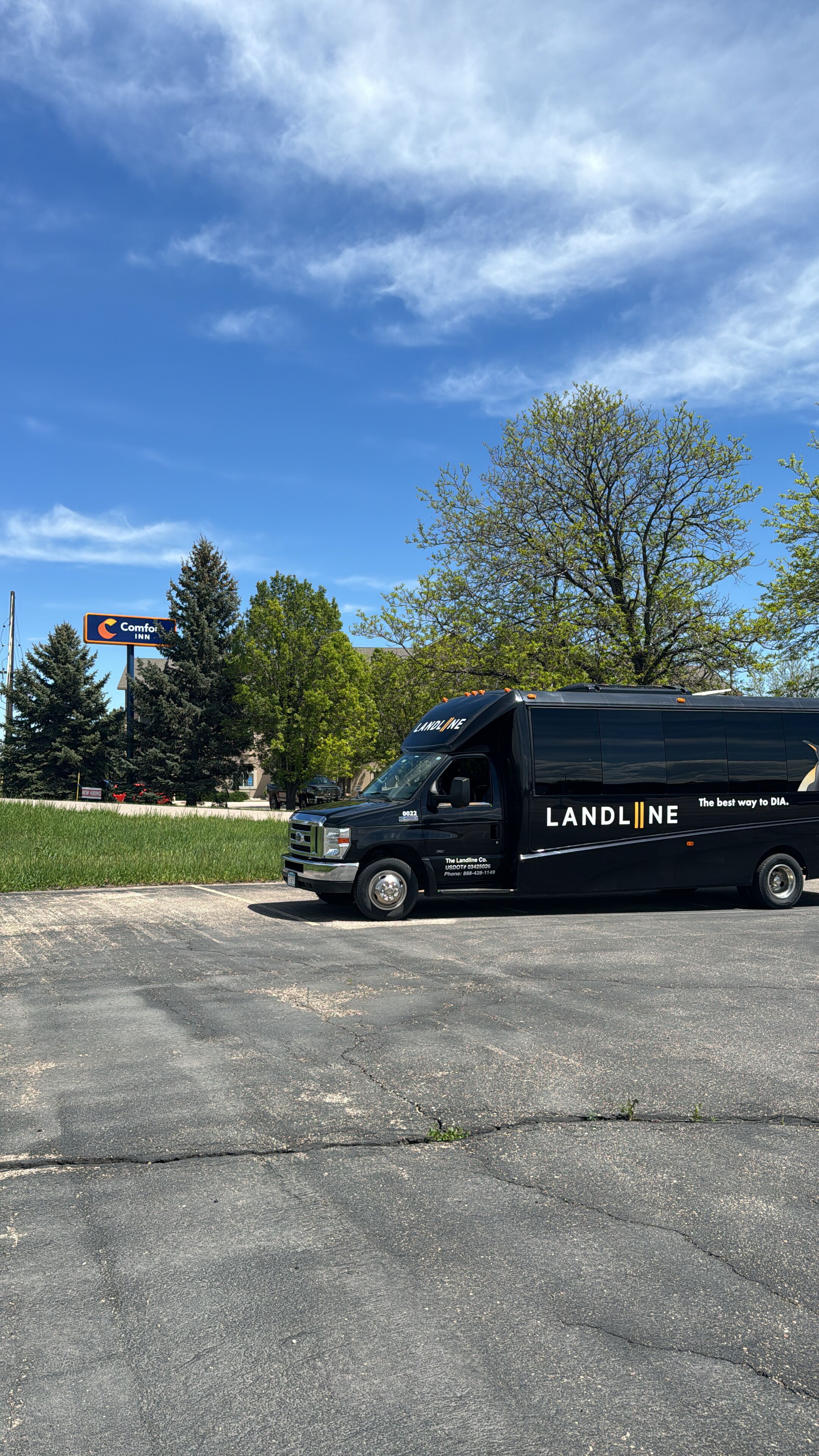 Un fourgon noir de la société Landline est stationné sur un parking, avec une enseigne « Comfort Inn » en arrière-plan.