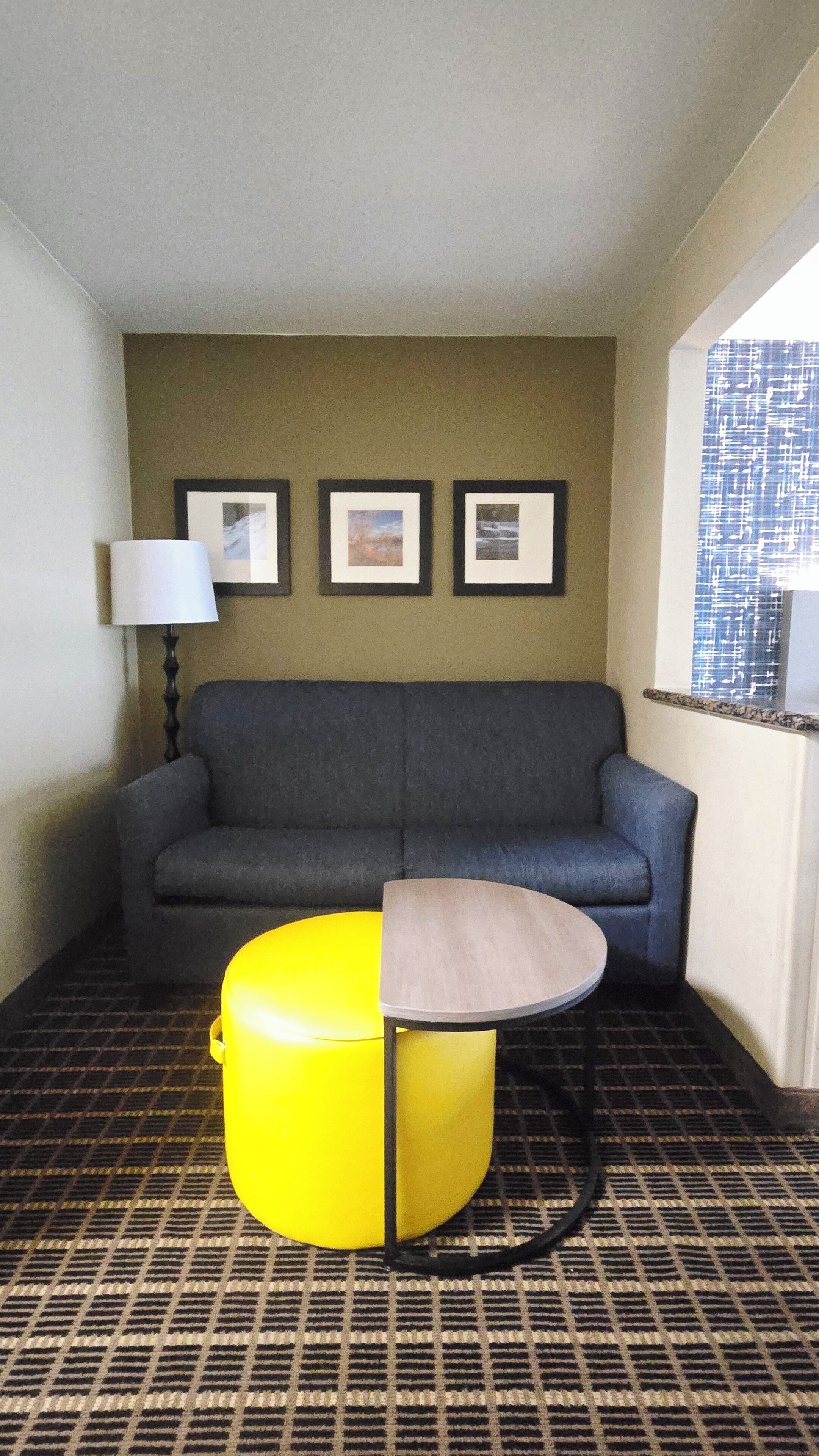 A room with a sofa, a small table, a lamp, and three framed pictures on the wall.
