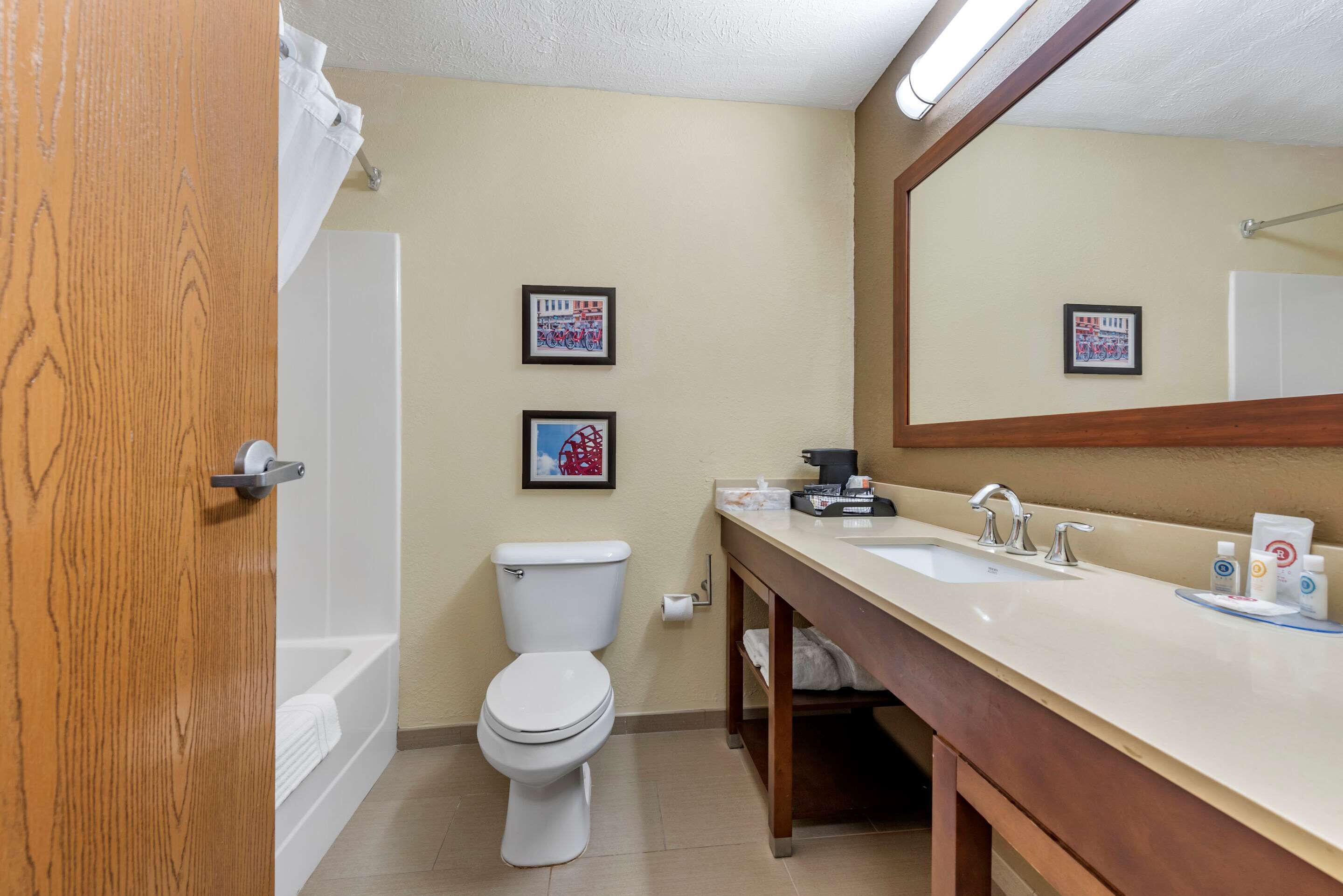 A bathroom with a toilet, sink, and bathtub. There are two framed pictures on the wall.