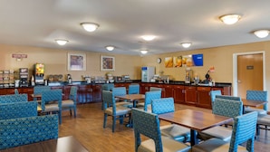 Un espace de restauration d'hôtel comprenant plusieurs tables et chaises, un comptoir de café et divers appareils de cuisine.