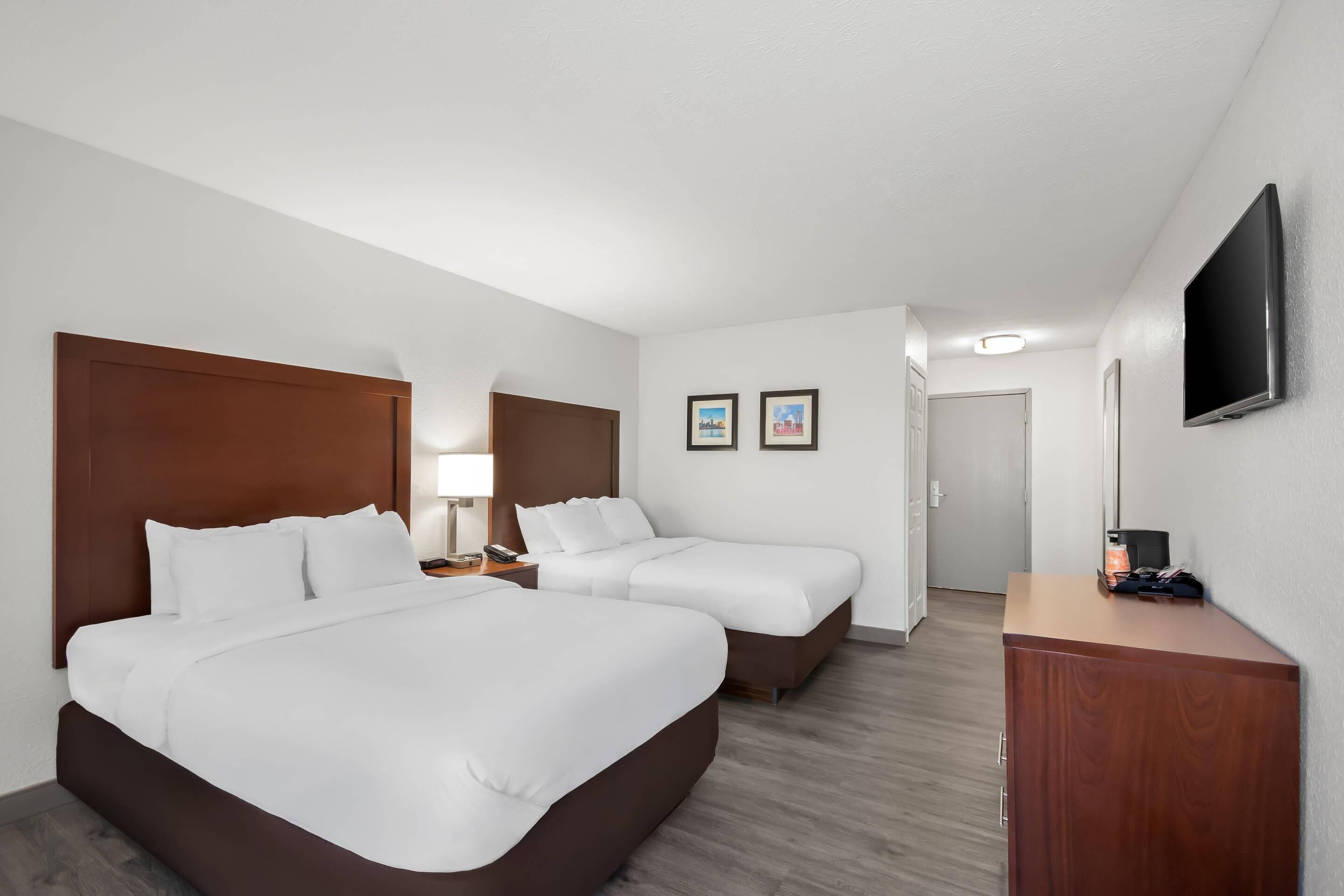 Une chambre d’hôtel avec deux lits, un bureau, une télévision et une porte.
