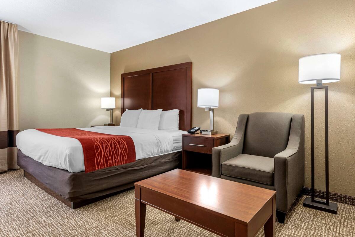 A hotel room with a bed, bedside tables, a chair, and a desk.
