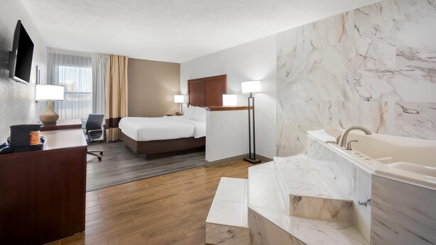 Une chambre d’hôtel comprenant un lit, un bureau et une grande salle de bain avec une baignoire et un lavabo.