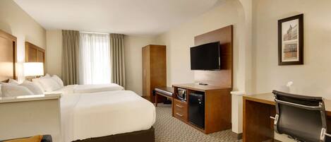 Una camera d'albergo con un letto grande, una scrivania con un computer, una televisione e una sedia.