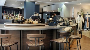 Zona de bar moderna con una variedad de botellas de licores, una máquina de café y un letrero de Starbucks.