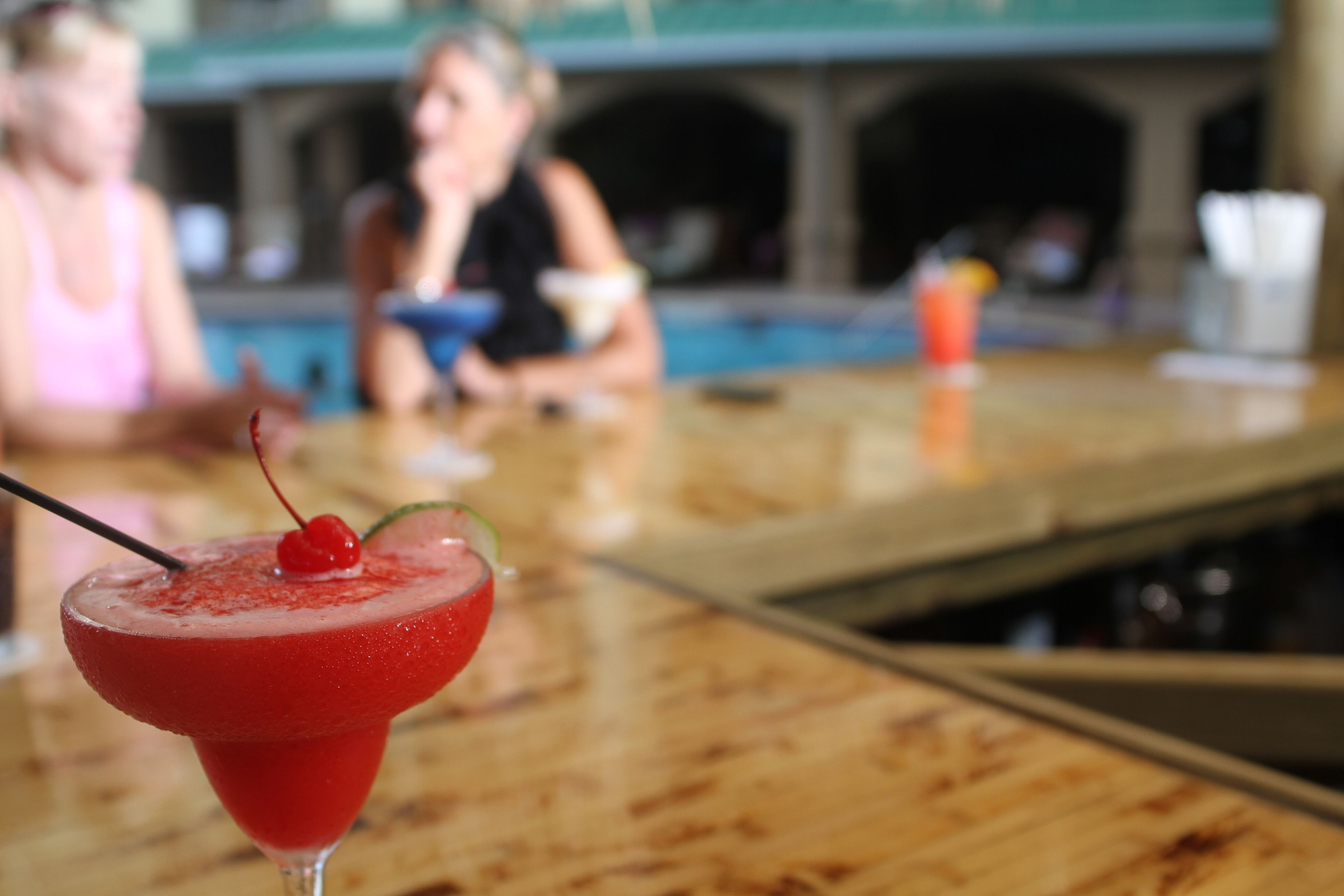 Ein Cocktail mit Kirsche auf einer Bar.