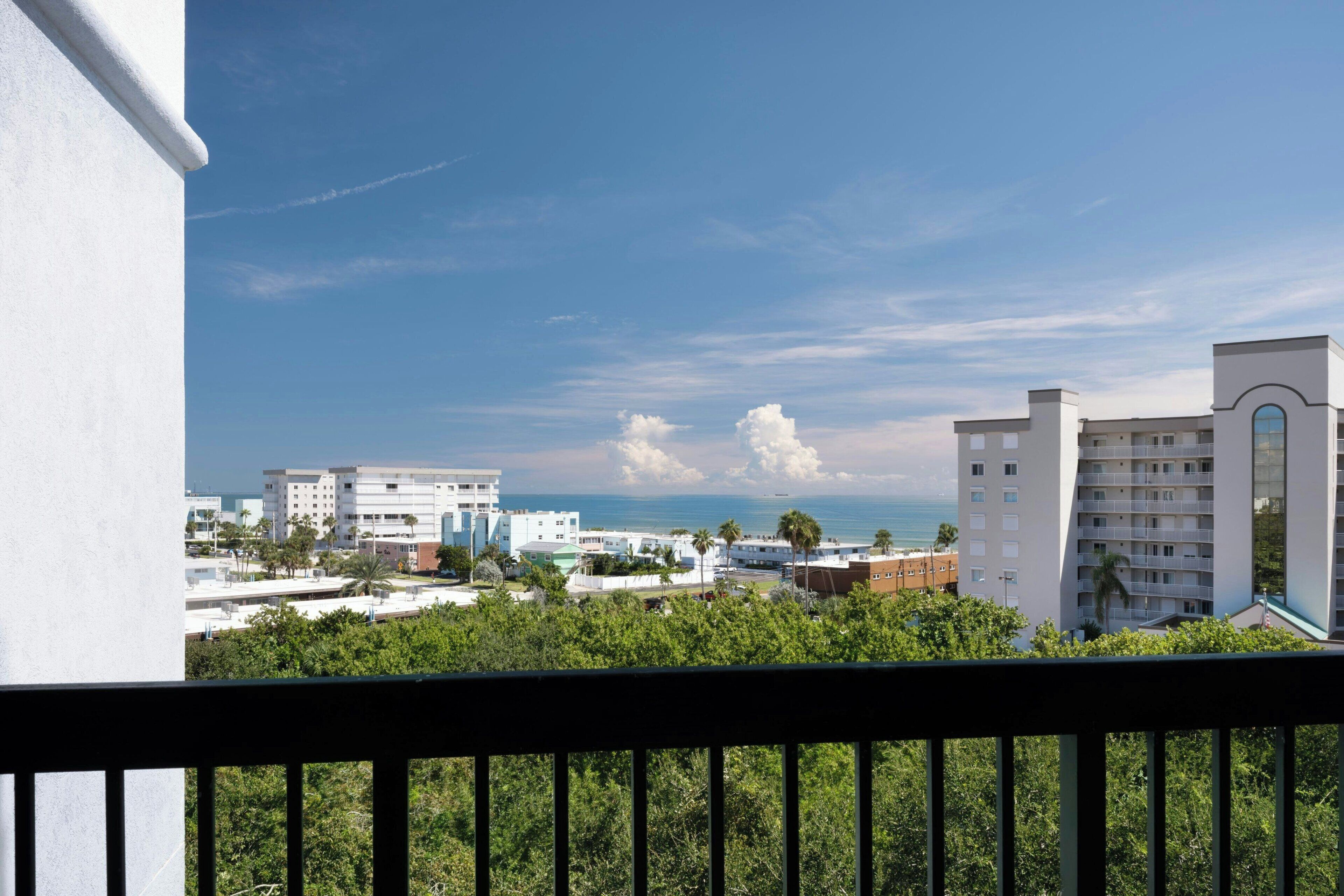 A view of a coastal cityscape with buildings, a clear sky, and the ocean in the background.