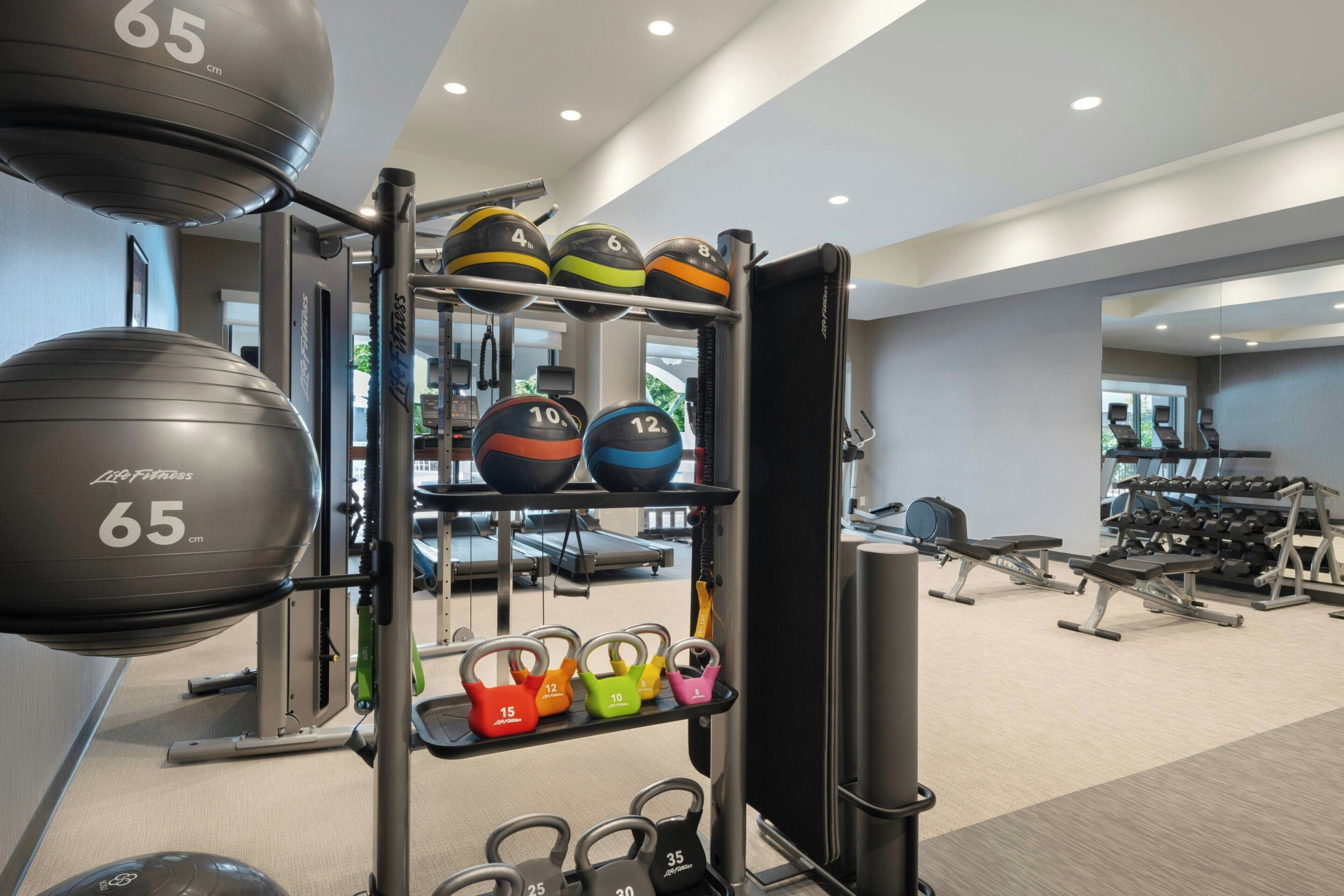 A gym with exercise equipment, including kettlebells, medicine balls, and dumbbells.