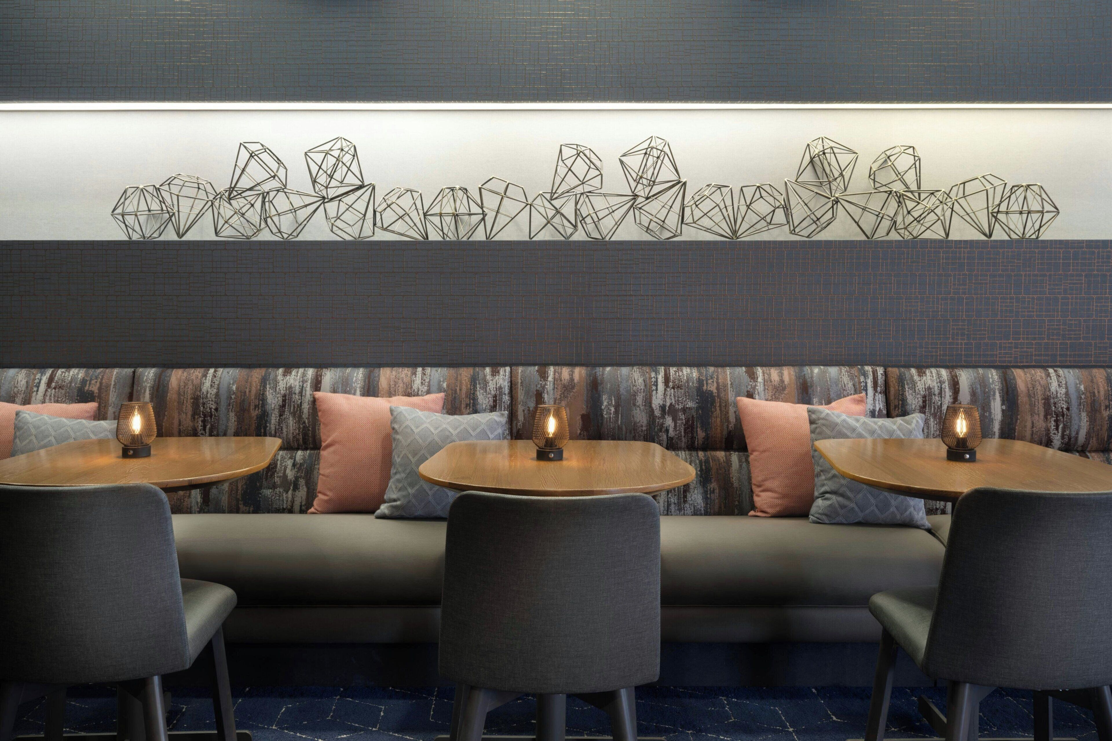 Un intérieur moderne avec un canapé, deux tables rondes et une œuvre d’art géométrique accrochée au mur.