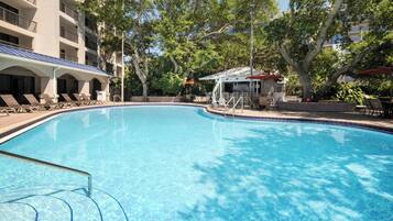 Una piscina al aire libre, sombrillas, sillones reclinables de piscina