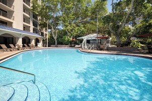 Una piscina al aire libre, sombrillas, sillones reclinables de piscina