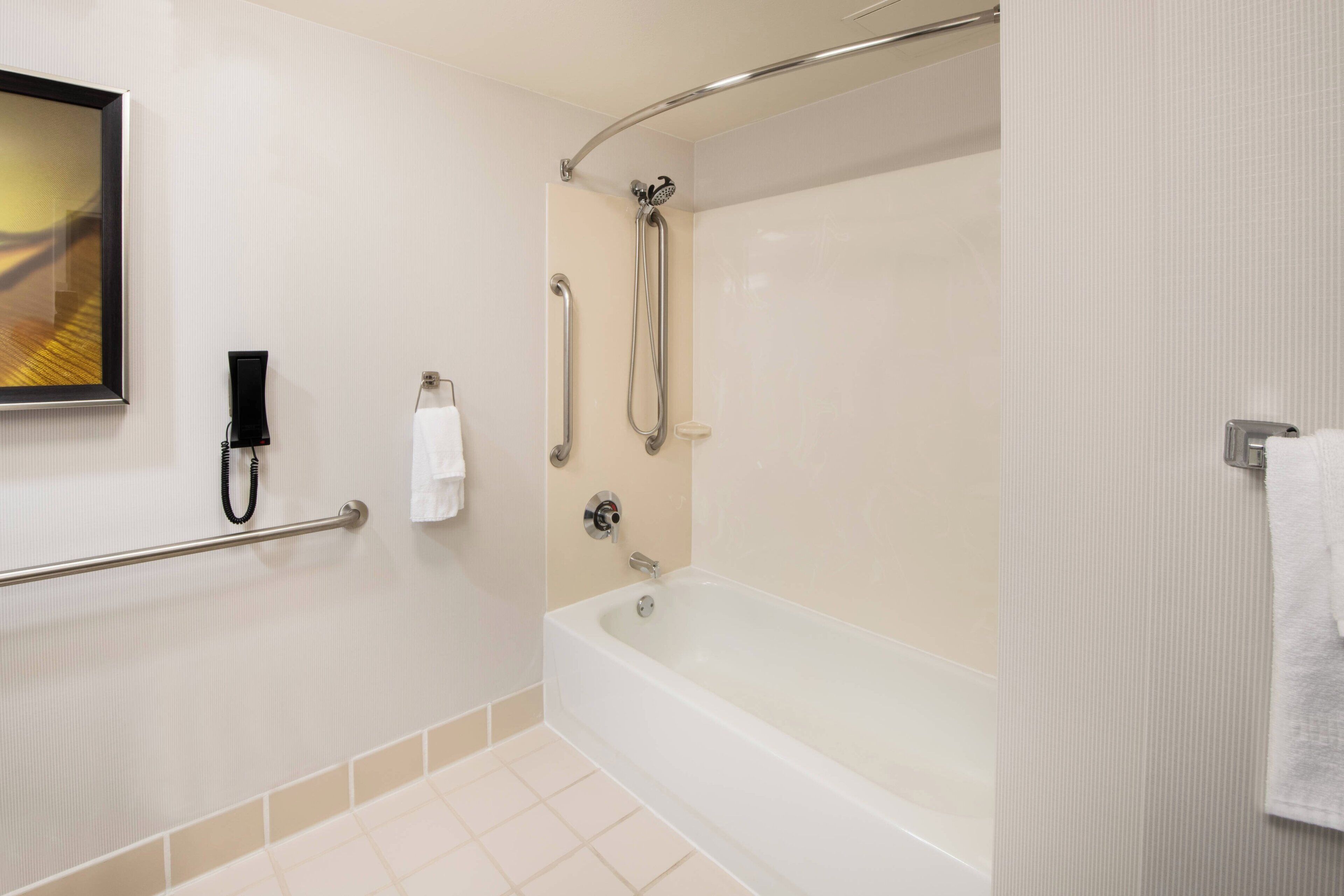 Un baño moderno con bañera, ducha y barras de apoyo.