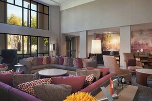 Un amplio salón con un sofá modular, sillones, una mesa de centro y una estantería.