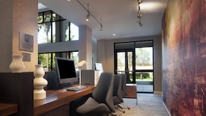 An office with a wooden desk, multiple chairs, a computer, and a large window.