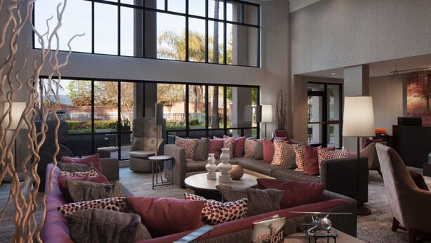 A spacious living area with a large sofa set, a coffee table, and a seating area with a lamp and a painting.