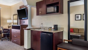 A compact hotel room with a kitchenette, a flat-screen TV, a refrigerator, a microwave, a coffee maker, a desk with a chair, and a sofa. - Comfort Suites Woodstock - Atlanta North (Woodstock)