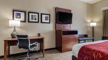 Habitación de hotel con cama, escritorio, silla, televisor y cuadros en la pared.