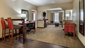 A hotel room with a desk, two chairs, a television, and a large mirror. - Comfort Suites Woodstock - Atlanta North (Woodstock)