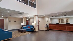 A hotel lobby with a reception desk, blue seating area, and a large window. - Comfort Suites Woodstock - Atlanta North (Woodstock)