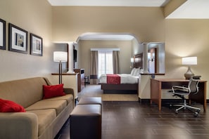 A hotel room with a sofa, a bed, a desk, a chair, and a mirror. - Comfort Suites Woodstock - Atlanta North (Woodstock)