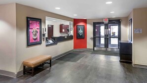A hotel lobby with a bench, a reception desk, a mirror, and an exit door. - Extended Stay America Suites Salt Lake City West Valley Ctr (West Valley City)