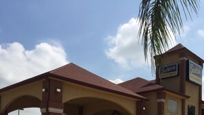 A hotel with a covered entrance, a parking lot, and a sign for 'Scotts Inn & Suites'. - Scottish Inn & Suites - Hobby Airport (Houston)